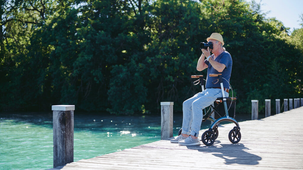 Aeltere Person macht Pause auf dem Rollator